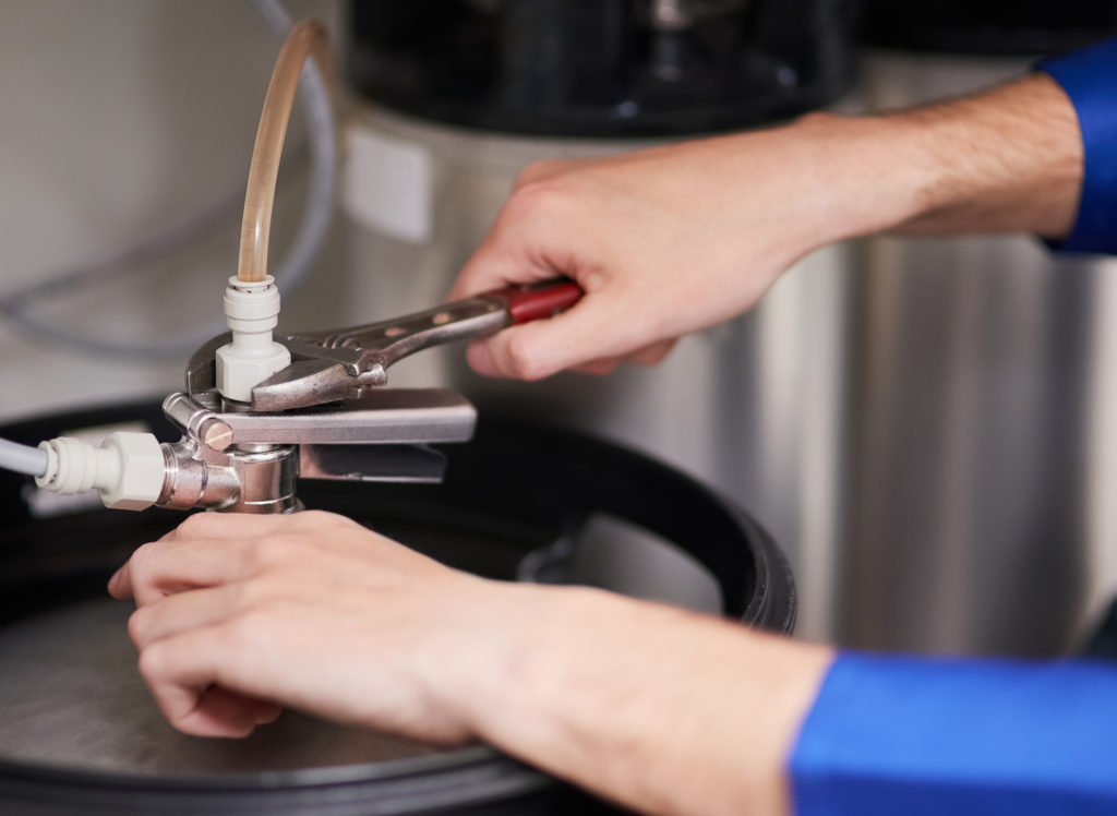 Cropped shot of a handyman repairing a pipe on a water heater.