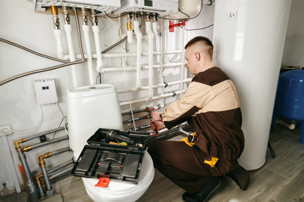 Young worker repairing pipes in lavatory